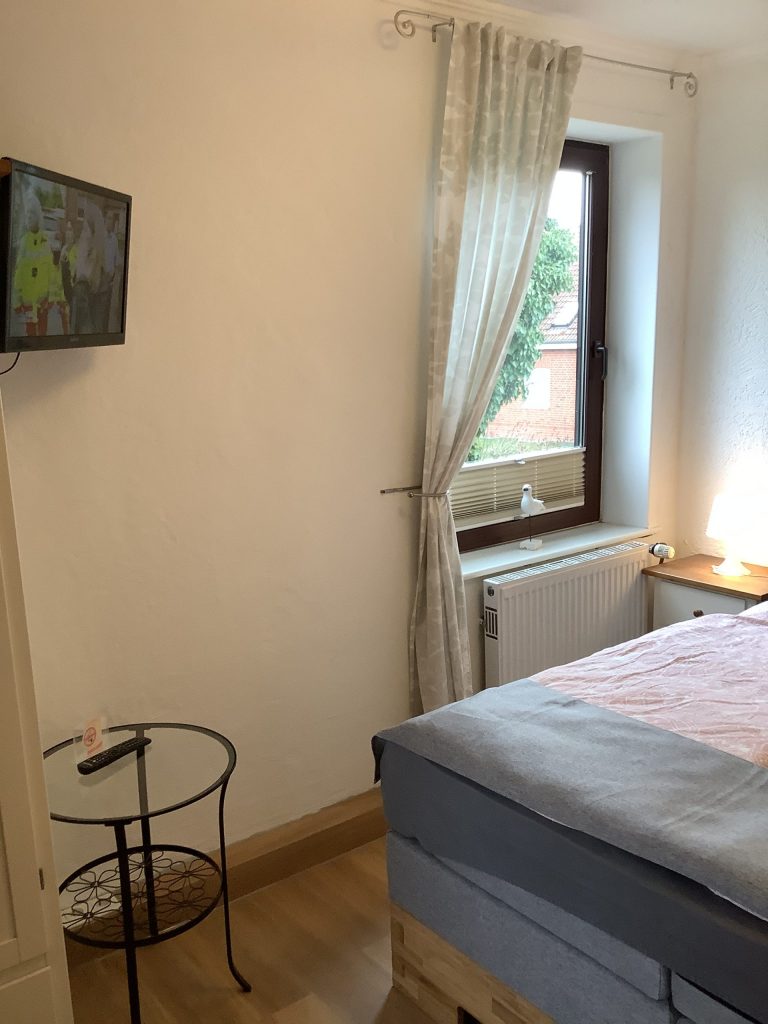 Schlafzimmer mit Fernseher und Fenster