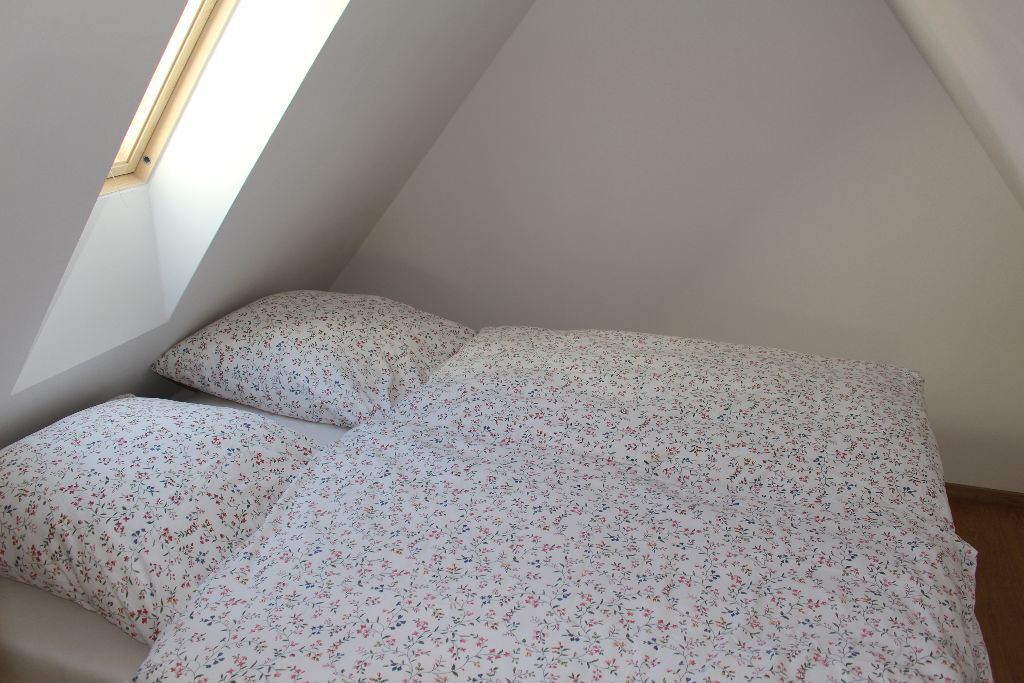 Dachzimmer mit Bett und Fenstern